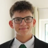 Artur Siuda Martin wearing glasses, a suit and green tie